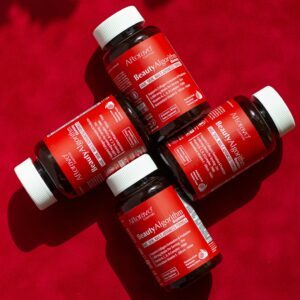 Top view of BeautyAlgorithm vitamin supplements on red background for hair and skin health.