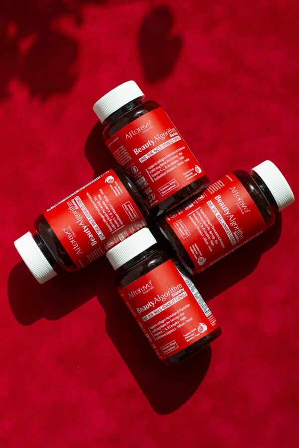 Top view of BeautyAlgorithm vitamin supplements on red background for hair and skin health.