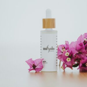 Elegant skincare serum with pink bougainvillea in a minimalist, bright composition.